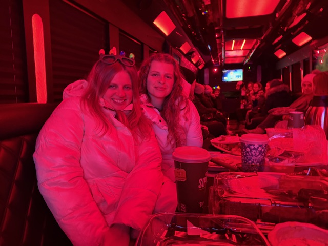 Friends enjoying a party bus ride with red lighting during a concert event transportation service by Nite Trane Transportation